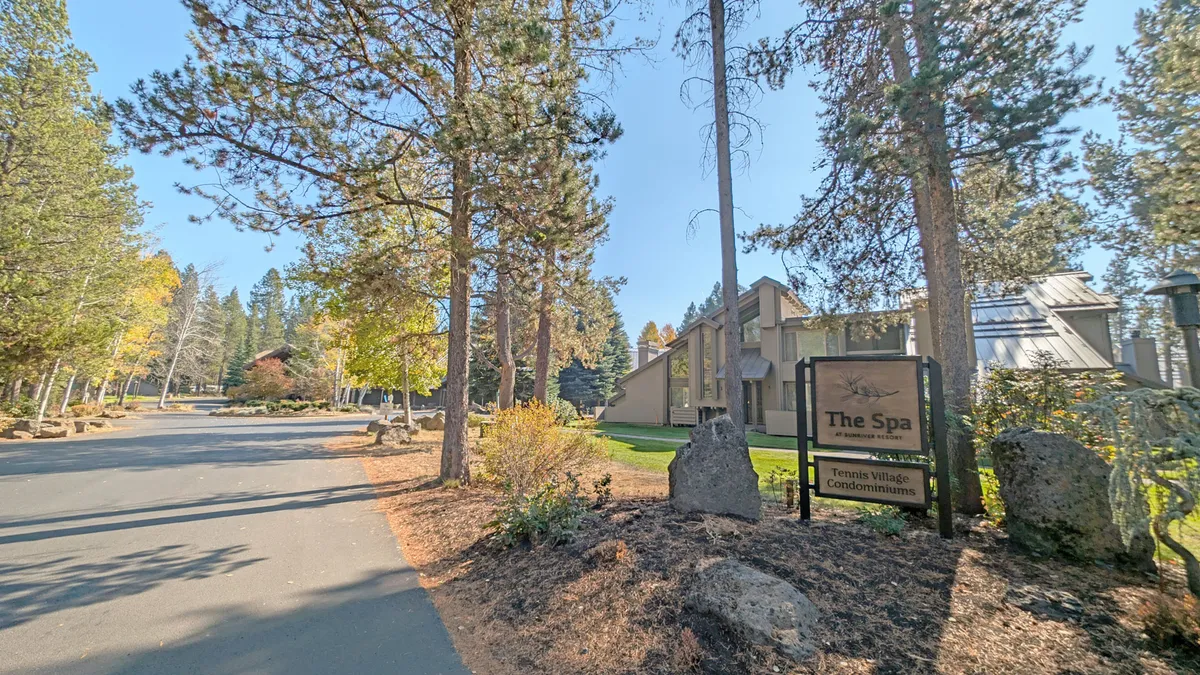 An exterior view of the on-site spa area with its distinctive sign, surrounded by mature trees and the condo’s architectural lines. The tranquil setting hints at relaxation after a day outdoors, with the natural environment front and center.